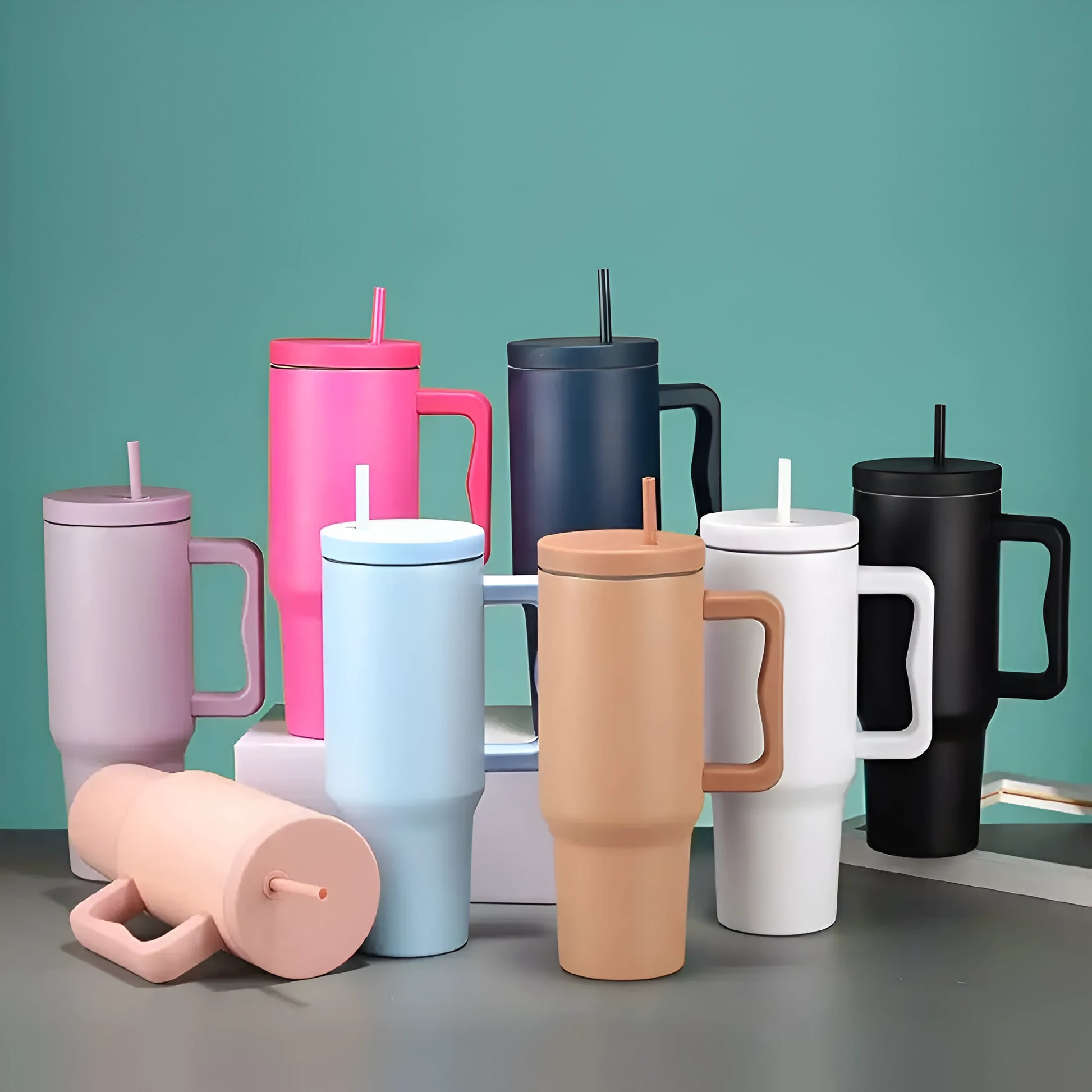 Collection of colorful tumblers with handles and straws on a green background