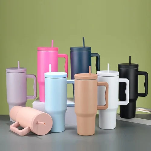 Collection of colorful tumblers with handles and straws on a green background